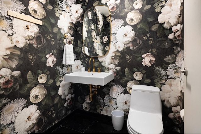 545 W 110th St Unit 6Eg, New York City, NY 10025 - bathroom with marble look tiles, toilet, a sink, wallpapered walls, and baseboards