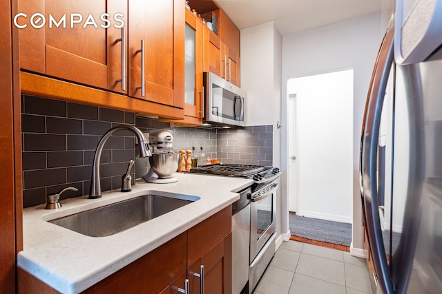 191 Willoughby St Unit 8J, New York City, NY 11201 - kitchen featuring appliances with stainless steel finishes, a sink, brown cabinetry, light countertops, and light tile patterned flooring