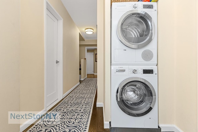 345 E 56th St Unit 3F, New York City, NY 10022 - washroom featuring estacked washer and dryer, baseboards, and wood finished floors