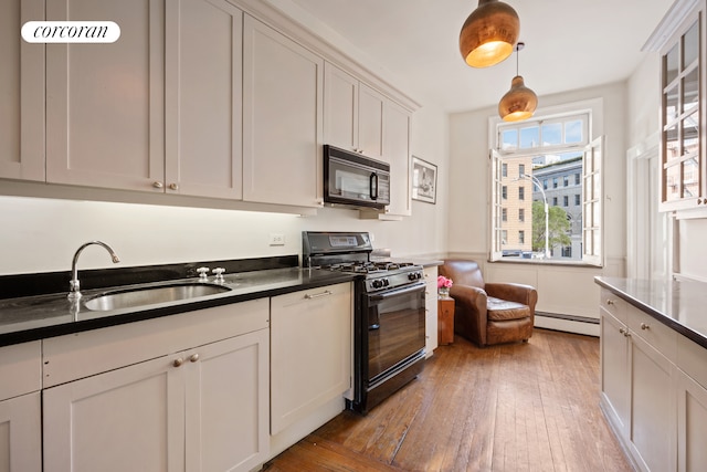 168 Waverly Place Upper, New York City, NY 10014 - kitchen featuring black appliances, light wood finished floors, dark countertops, and a baseboard radiator