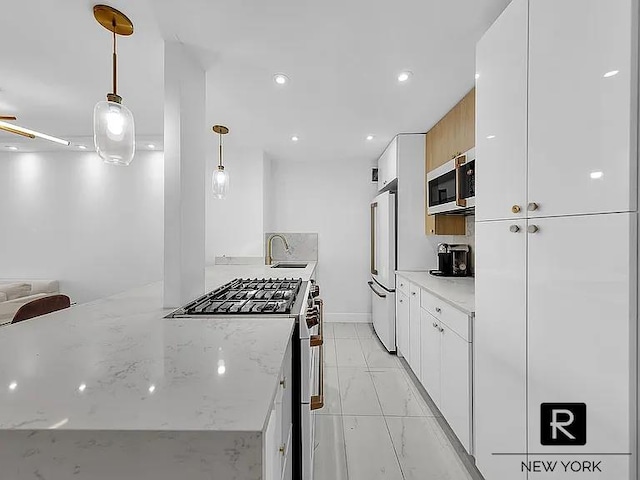 kitchen with high quality appliances, light marble finish flooring, white cabinetry, a sink, and light stone countertops