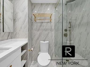 full bath with a marble finish shower, vanity, tile walls, toilet, and marble finish floors
