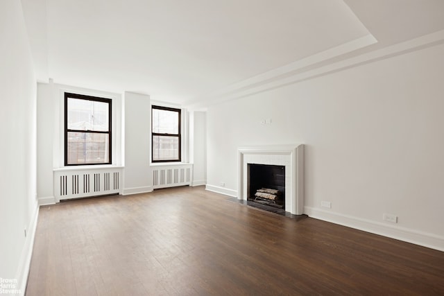 unfurnished living room featuring radiator heating unit, wood finished floors, a fireplace with flush hearth, and baseboards