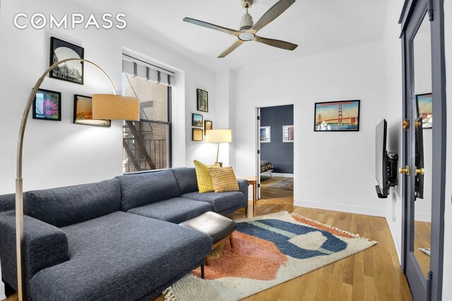living area featuring ceiling fan, baseboards, and wood finished floors