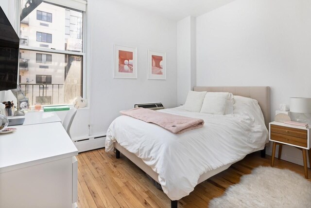bedroom featuring light wood-style flooring and a baseboard radiator