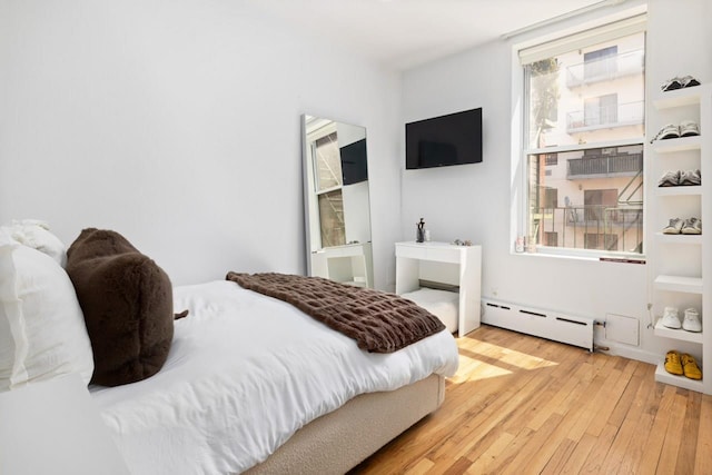 bedroom with baseboard heating and wood-type flooring