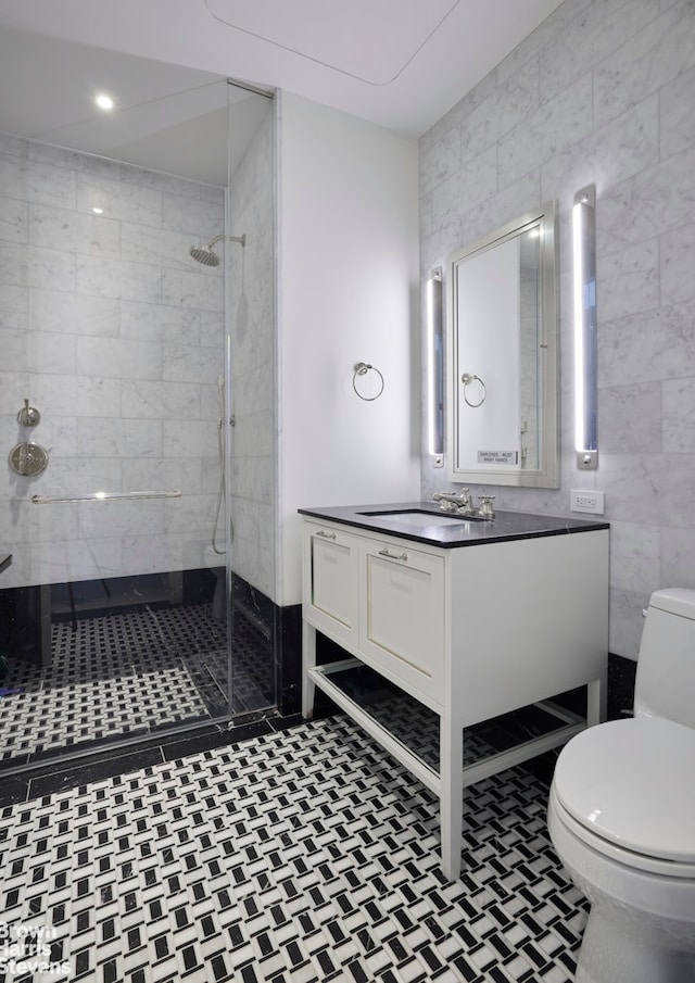 full bath with toilet, a tile shower, tile walls, and vanity