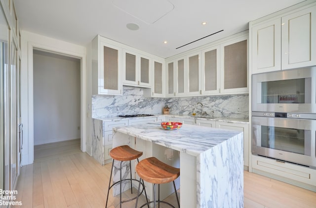 kitchen featuring decorative backsplash, light wood-style flooring, a kitchen island, and recessed lighting