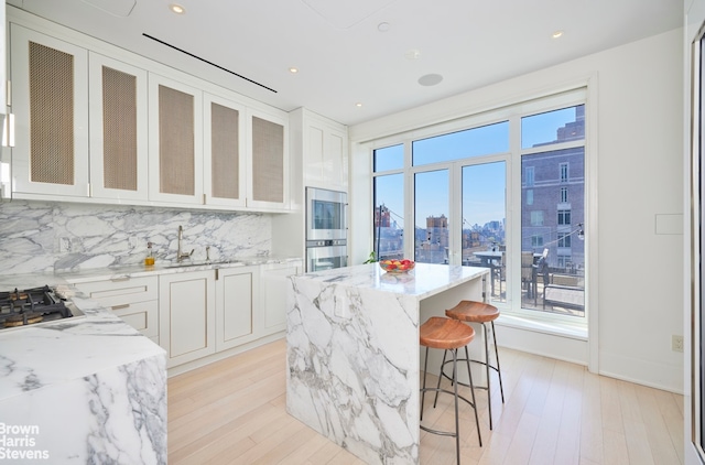 kitchen with a city view, backsplash, light stone countertops, a kitchen bar, and recessed lighting