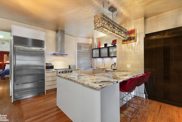 251 W 95th St Unit 2N, New York City, NY 10025 - kitchen with wall chimney exhaust hood, stainless steel built in refrigerator, wood finished floors, a sink, and a kitchen bar