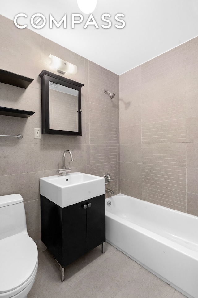 full bath with toilet, shower / bath combination, tile walls, vanity, and tile patterned flooring