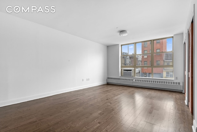 unfurnished room featuring dark wood-type flooring, a baseboard heating unit, baseboards, and cooling unit