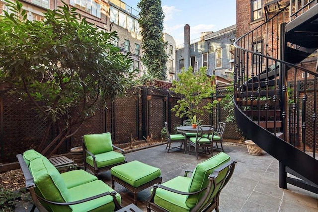 view of patio featuring outdoor dining area, fence, and stairway