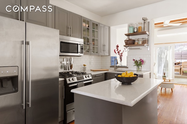 171 Monitor St, New York City, NY 11222 - kitchen featuring appliances with stainless steel finishes, gray cabinetry, open shelves, and backsplash