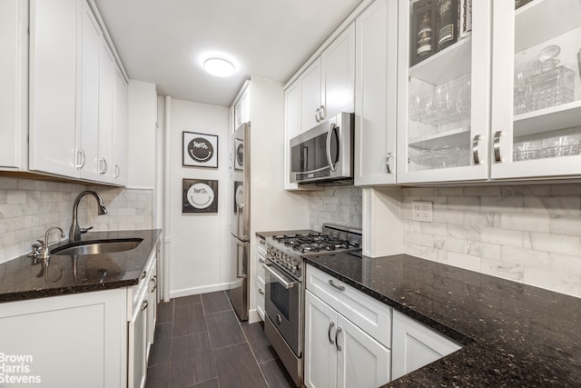 220 E 54th St Unit 8D, New York City, NY 10022 - kitchen featuring appliances with stainless steel finishes, a sink, dark stone counters, and white cabinets