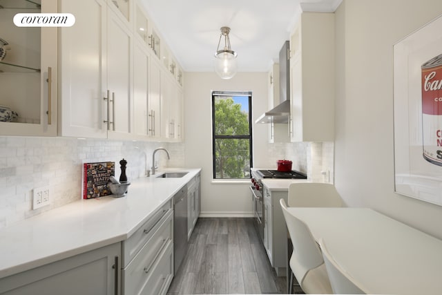 kitchen featuring a sink, wall chimney exhaust hood, appliances with stainless steel finishes, light countertops, and dark wood finished floors