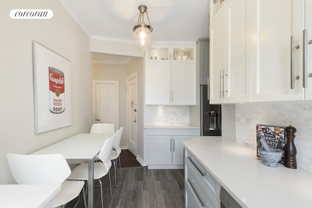 kitchen featuring light countertops, ornamental molding, backsplash, dark wood finished floors, and white cabinetry