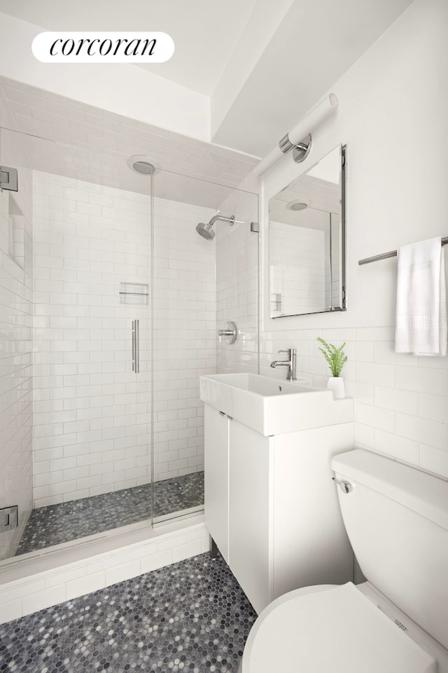 bathroom featuring tile walls, toilet, a shower stall, and vanity