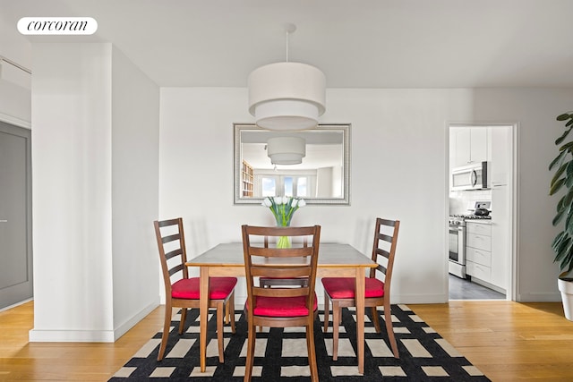 dining space with light wood-type flooring and baseboards