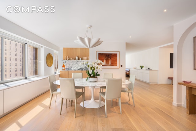 dining area featuring recessed lighting, arched walkways, and light wood-type flooring