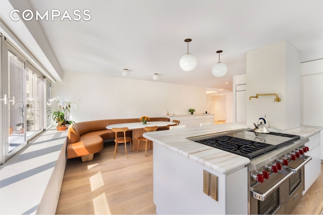 kitchen with white cabinetry, hanging light fixtures, and light wood-style floors