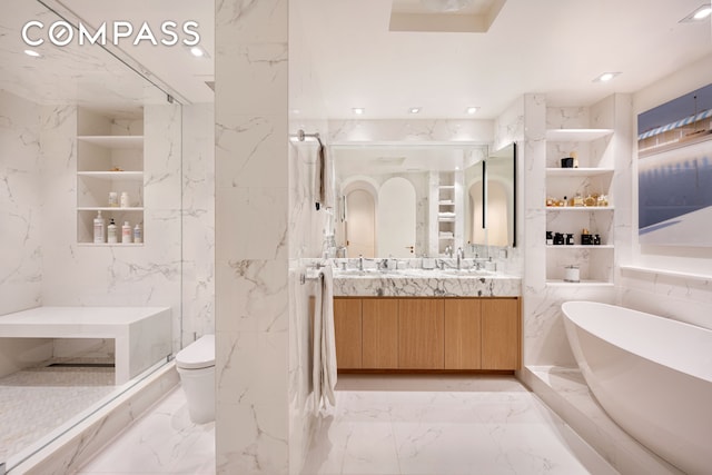 full bath with recessed lighting, stone wall, double vanity, marble finish floor, and a soaking tub