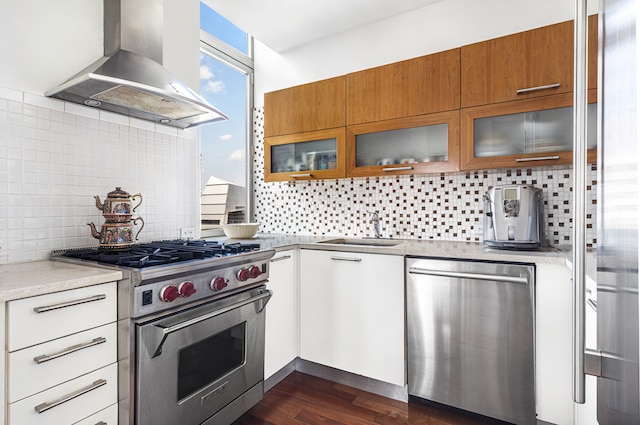 121 E 23rd St Phd, Phd, New York City, NY 10010 - kitchen featuring stainless steel appliances, wall chimney range hood, brown cabinets, and tasteful backsplash