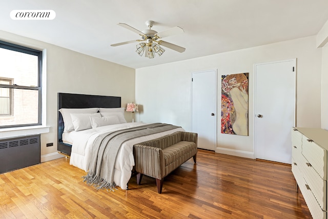 bedroom with radiator, light wood-style flooring, baseboards, and ceiling fan