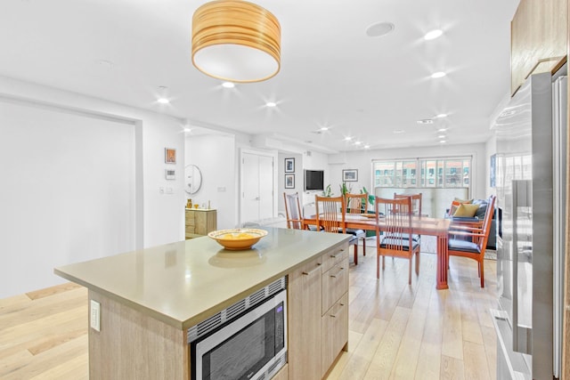kitchen featuring light brown cabinetry, appliances with stainless steel finishes, modern cabinets, a center island, and light wood finished floors
