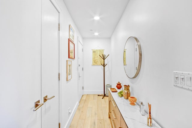 corridor featuring recessed lighting, baseboards, and light wood finished floors