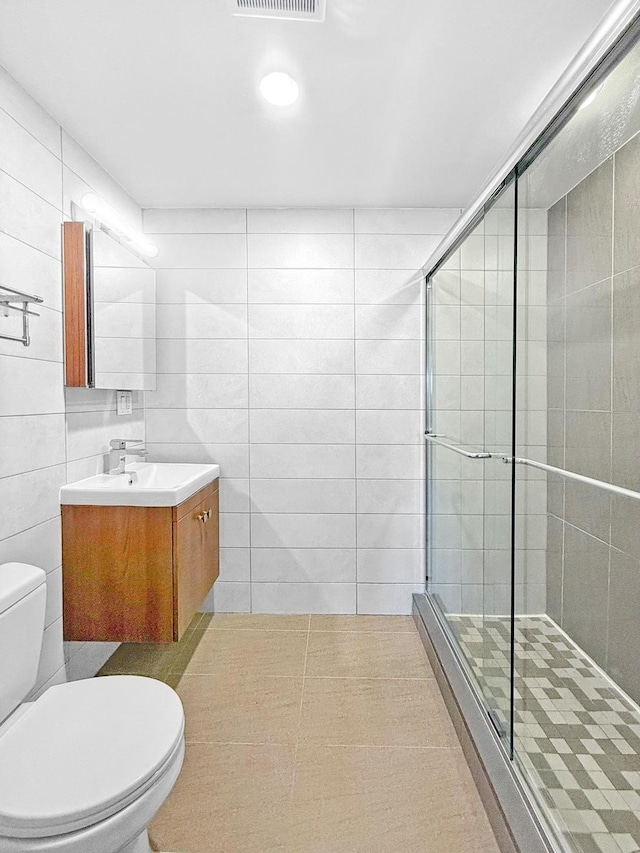 bathroom with vanity, visible vents, toilet, tile walls, and a shower stall