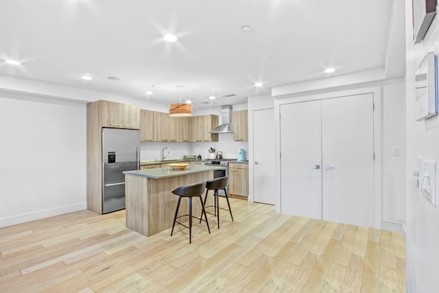 kitchen with a breakfast bar area, wall chimney exhaust hood, a center island, stainless steel appliances, and recessed lighting