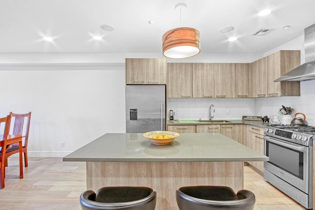 kitchen with a sink, a breakfast bar area, light brown cabinets, and stainless steel appliances