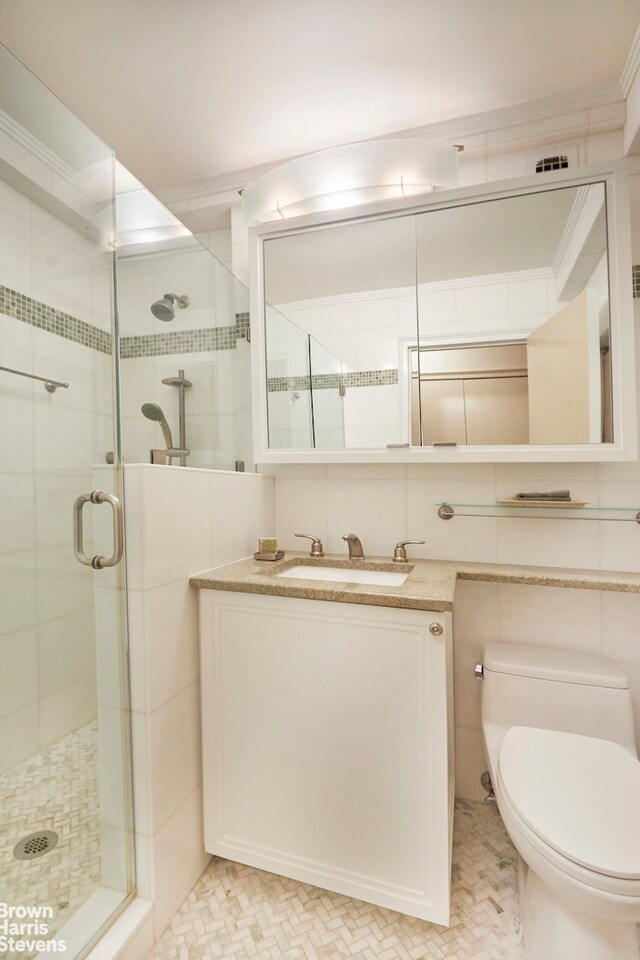 50 Park Ave Unit 5B, New York City, NY 10016 - bathroom with toilet, a shower stall, vanity, tile walls, and tile patterned flooring