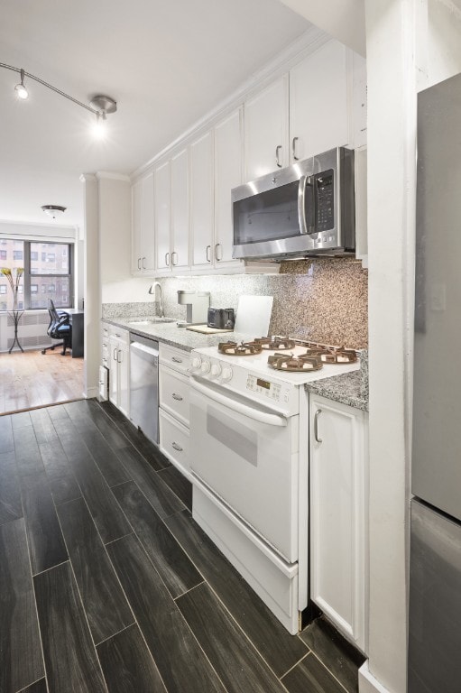 kitchen with appliances with stainless steel finishes, dark wood-type flooring, white cabinetry, and a sink