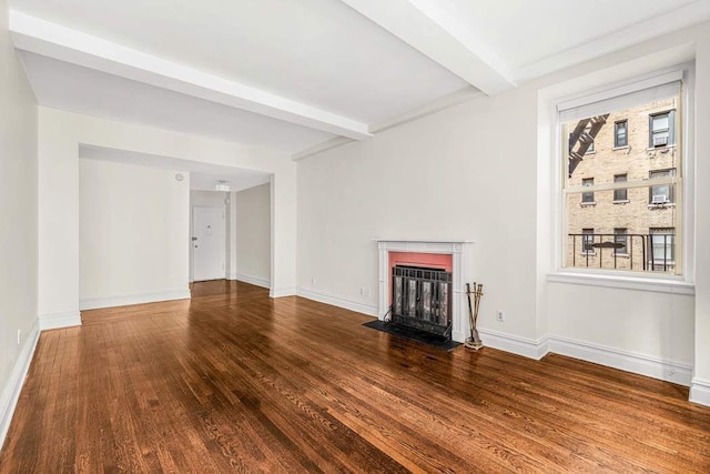unfurnished living room featuring beamed ceiling, wood finished floors, baseboards, and a fireplace with flush hearth