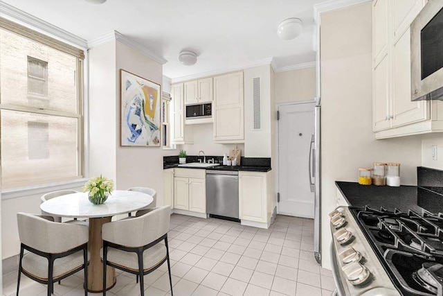 kitchen featuring dark countertops, appliances with stainless steel finishes, ornamental molding, and light tile patterned floors