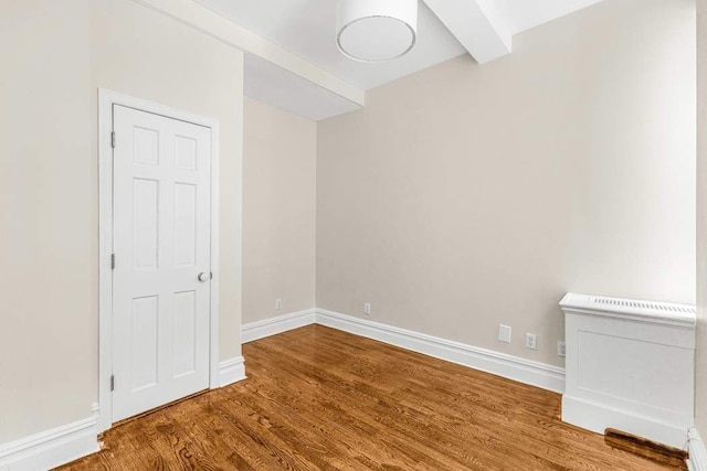spare room featuring a baseboard radiator, wood finished floors, and baseboards