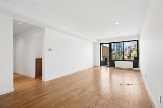 10-55 47th Ave Unit 5-E, New York City, NY 11101 - empty room featuring light wood-style flooring, recessed lighting, baseboards, and radiator heating unit