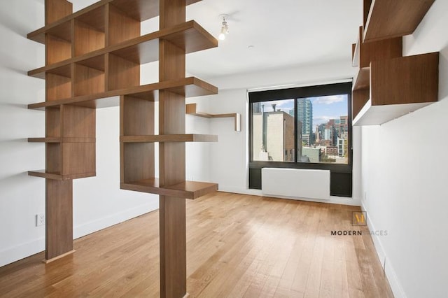 10-55 47th Ave Unit 5-E, New York City, NY 11101 - unfurnished living room featuring wood finished floors, baseboards, radiator, and a city view