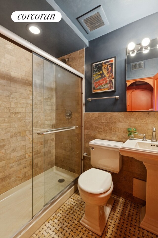 bathroom with tile walls, a stall shower, and toilet
