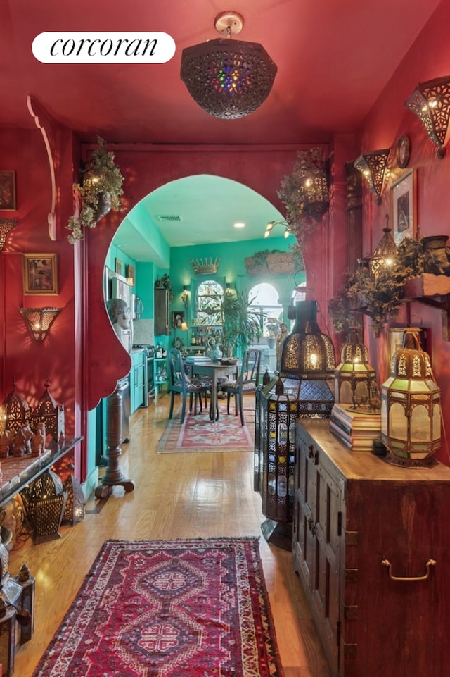 dining room with arched walkways and wood finished floors