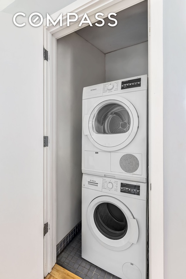 washroom featuring stacked washer / drying machine and baseboards