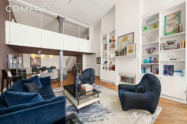 121 W 20th St Unit 2D, New York City, NY 10011 - living room with a high ceiling, light wood finished floors, built in features, and decorative columns