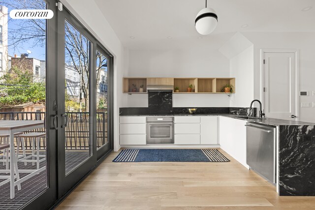 kitchen featuring white cabinets, open shelves, appliances with stainless steel finishes, a sink, and light wood-style flooring