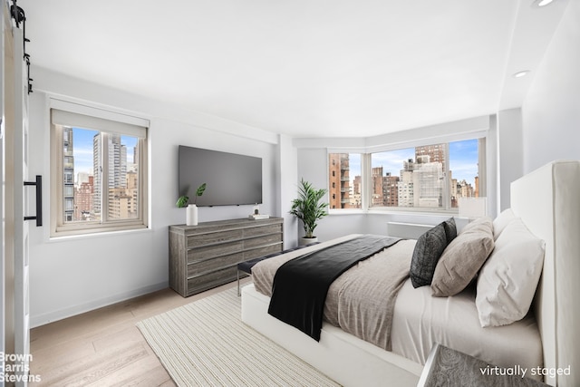 bedroom featuring recessed lighting, baseboards, wood finished floors, and multiple windows