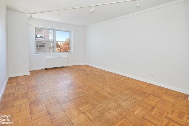 unfurnished room featuring baseboards, radiator heating unit, and rail lighting