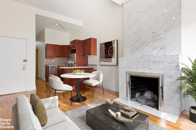 living area featuring track lighting, light wood-style flooring, a towering ceiling, and baseboards