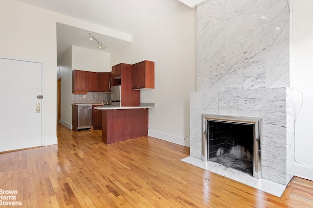 kitchen featuring a peninsula, light wood-style flooring, light countertops, track lighting, and dishwasher