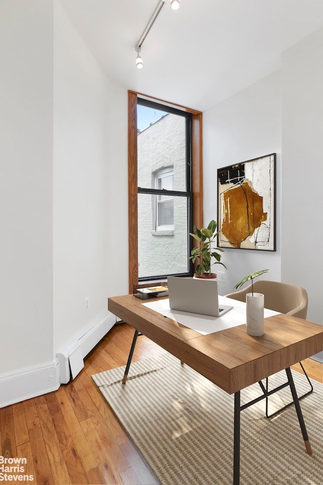 home office with light wood-type flooring, track lighting, baseboards, and a baseboard radiator